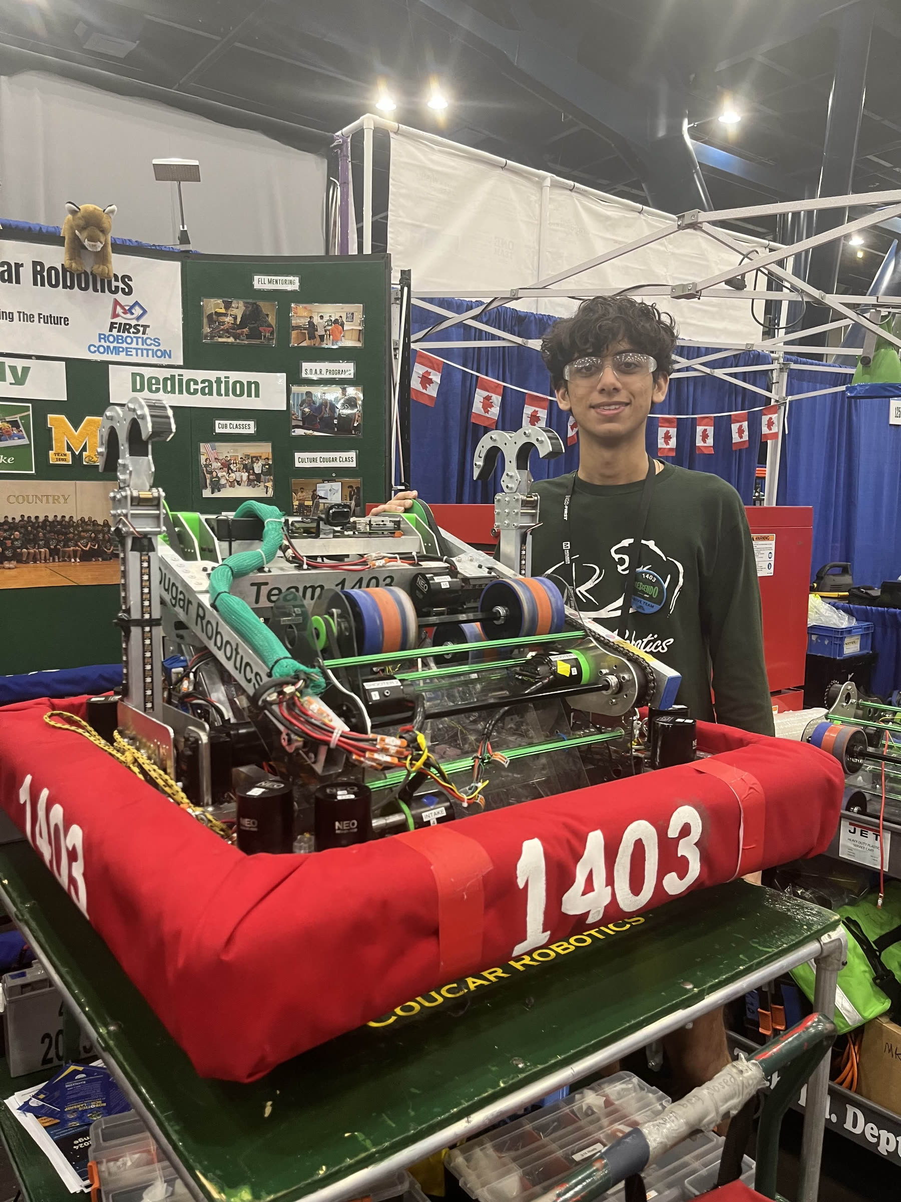 Krish Vatsa standing next to the finished 2024 competition robot in the team pit